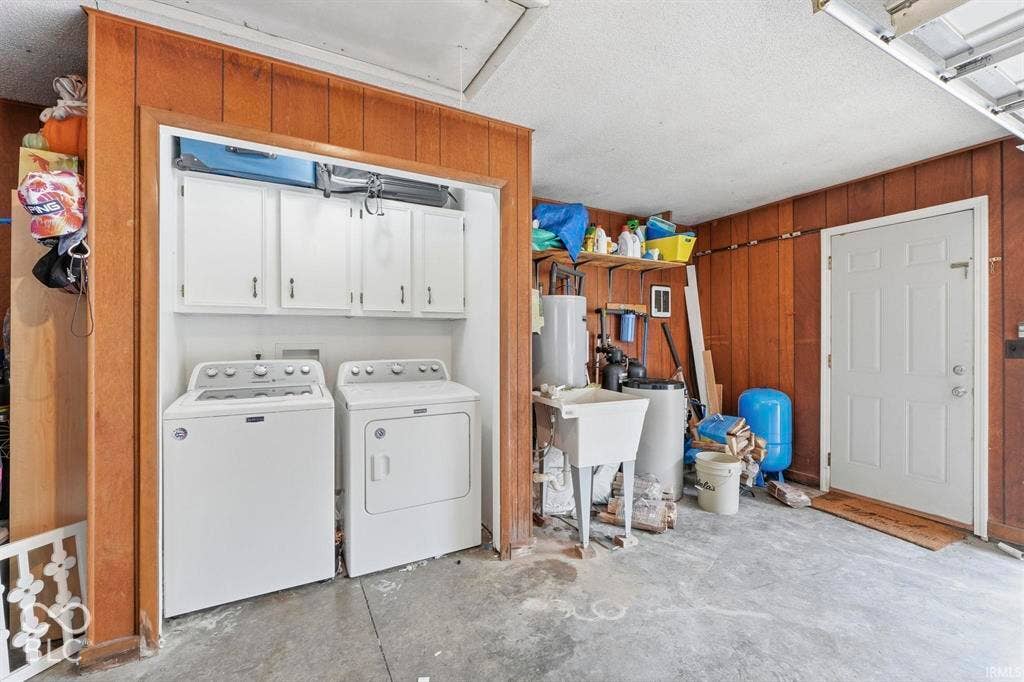 Spacious garage with wood-paneled walls, concrete flooring, and built-in cabinetry above the washer and dryer