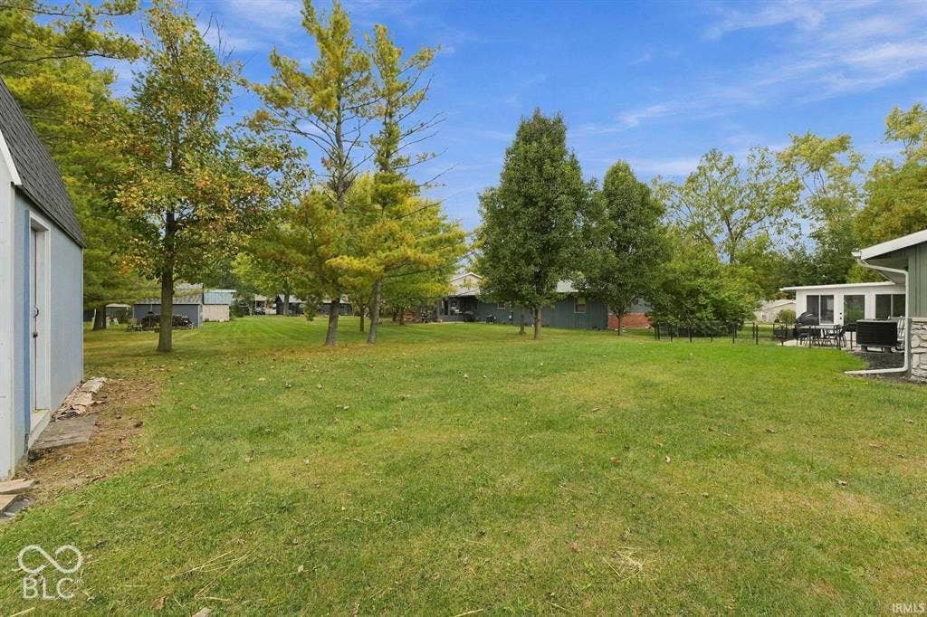 Expansive grounds featuring a level, manicured lawn with mature shade trees throughout