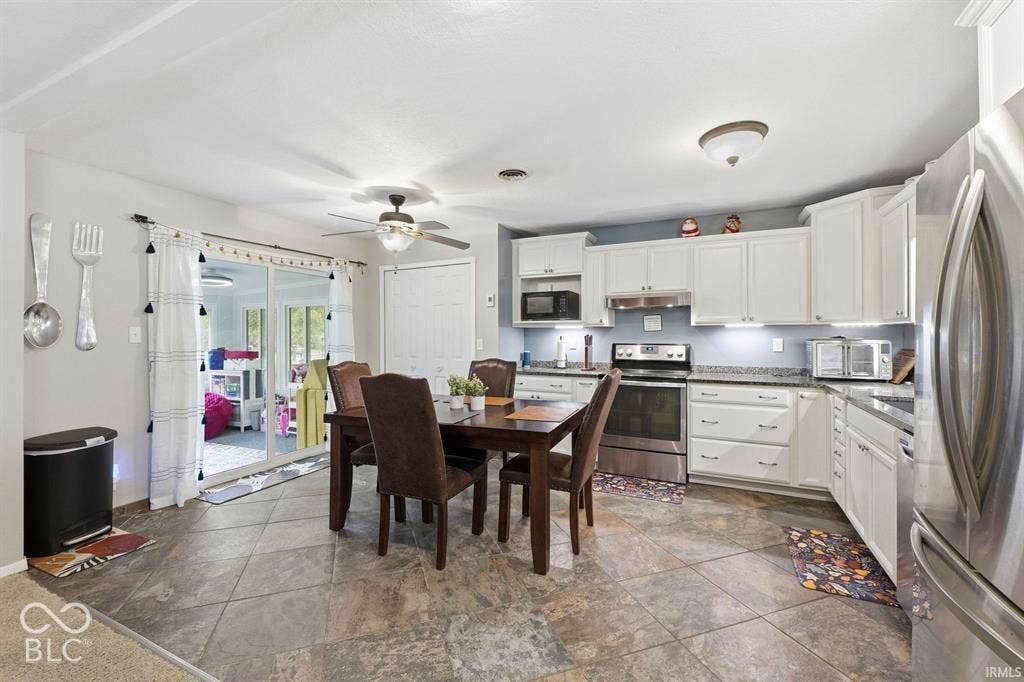 Kitchen featuring white cabinetry, stainless steel appliances, grey countertops, tile flooring, and sliding glass doors