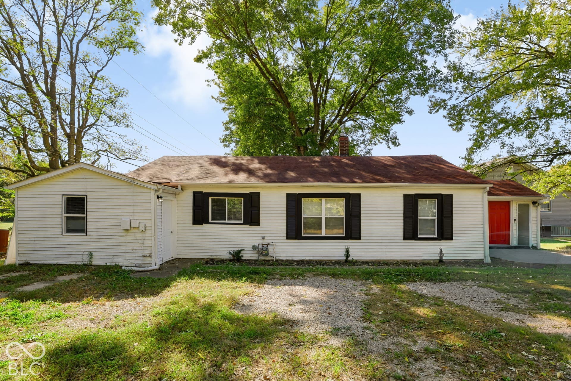 White siding exterior with a red entry door, dark shutters, and a shingle roof