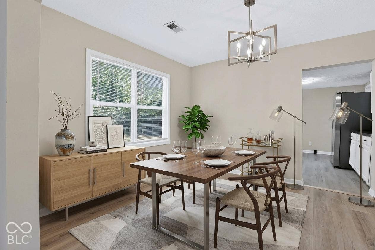 Open concept dining space featuring wood-finish flooring, a contemporary chandelier, a large window, and an arched entry to the adjacent kitchen