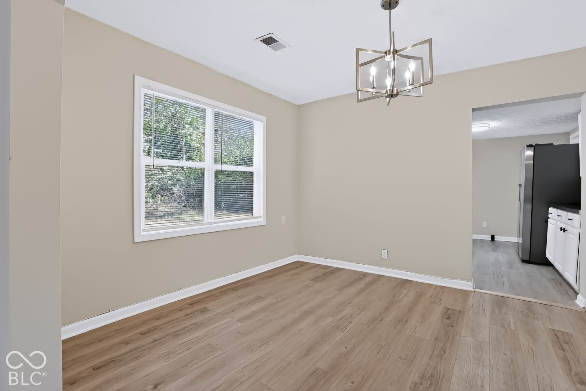 Recessed lighting, wood-finish flooring, neutral wall tones, modern chandelier, and an open doorway