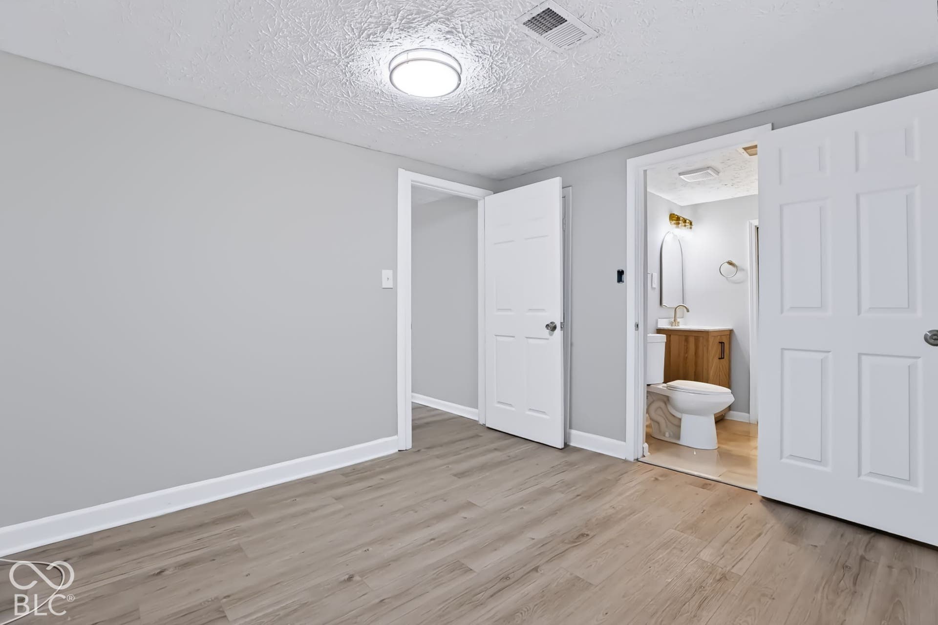 Wood-finish flooring, light gray wall paint, and overhead lighting