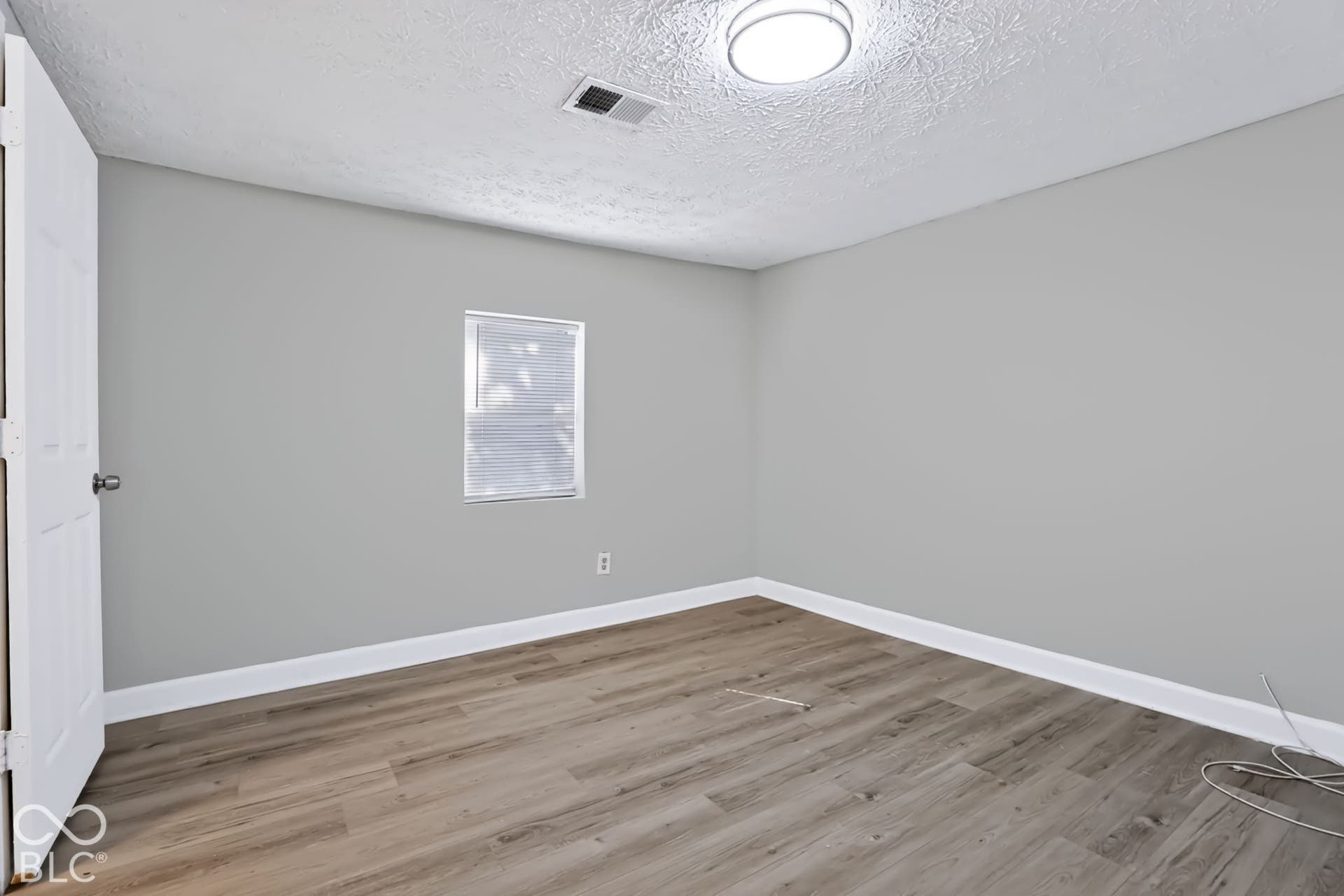 Wood-finish flooring, light gray walls, white trim, recessed lighting, and a white interior door