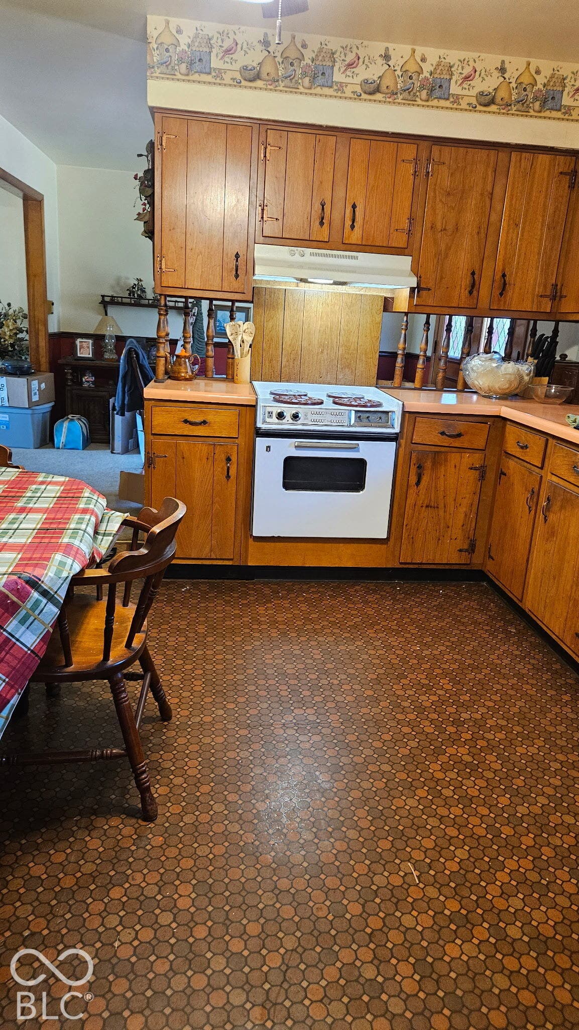 Wood cabinetry with coordinating countertops, white built-in oven and stovetop, and patterned flooring