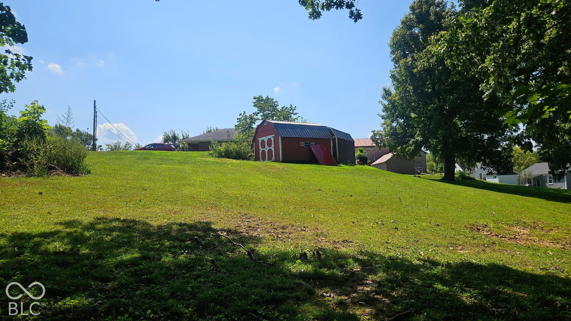 Expansive lawn with a red storage shed featuring a metal roof