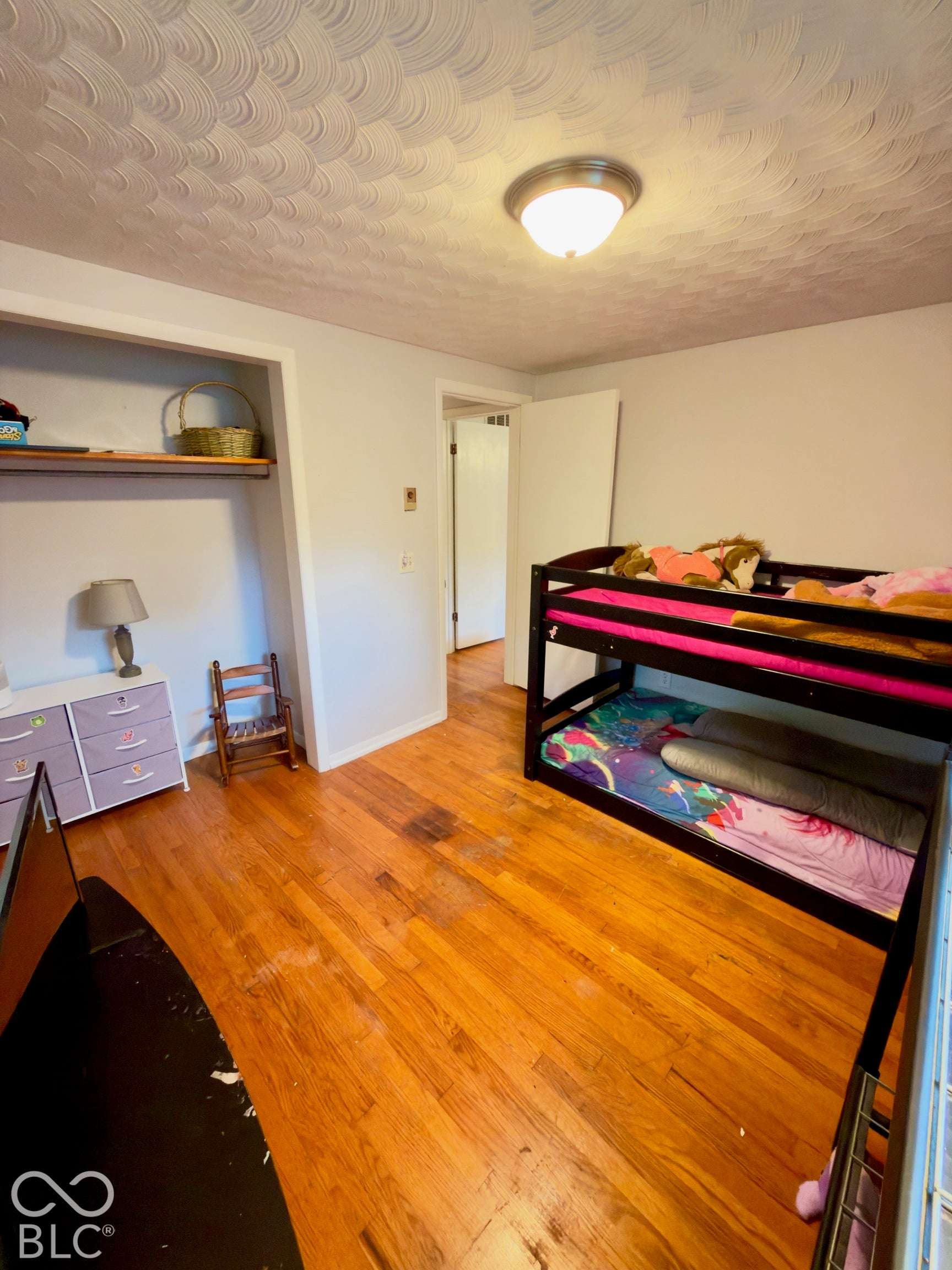 Room featuring wood-finish flooring, a scalloped-pattern ceiling, and a built-in recessed closet shelf