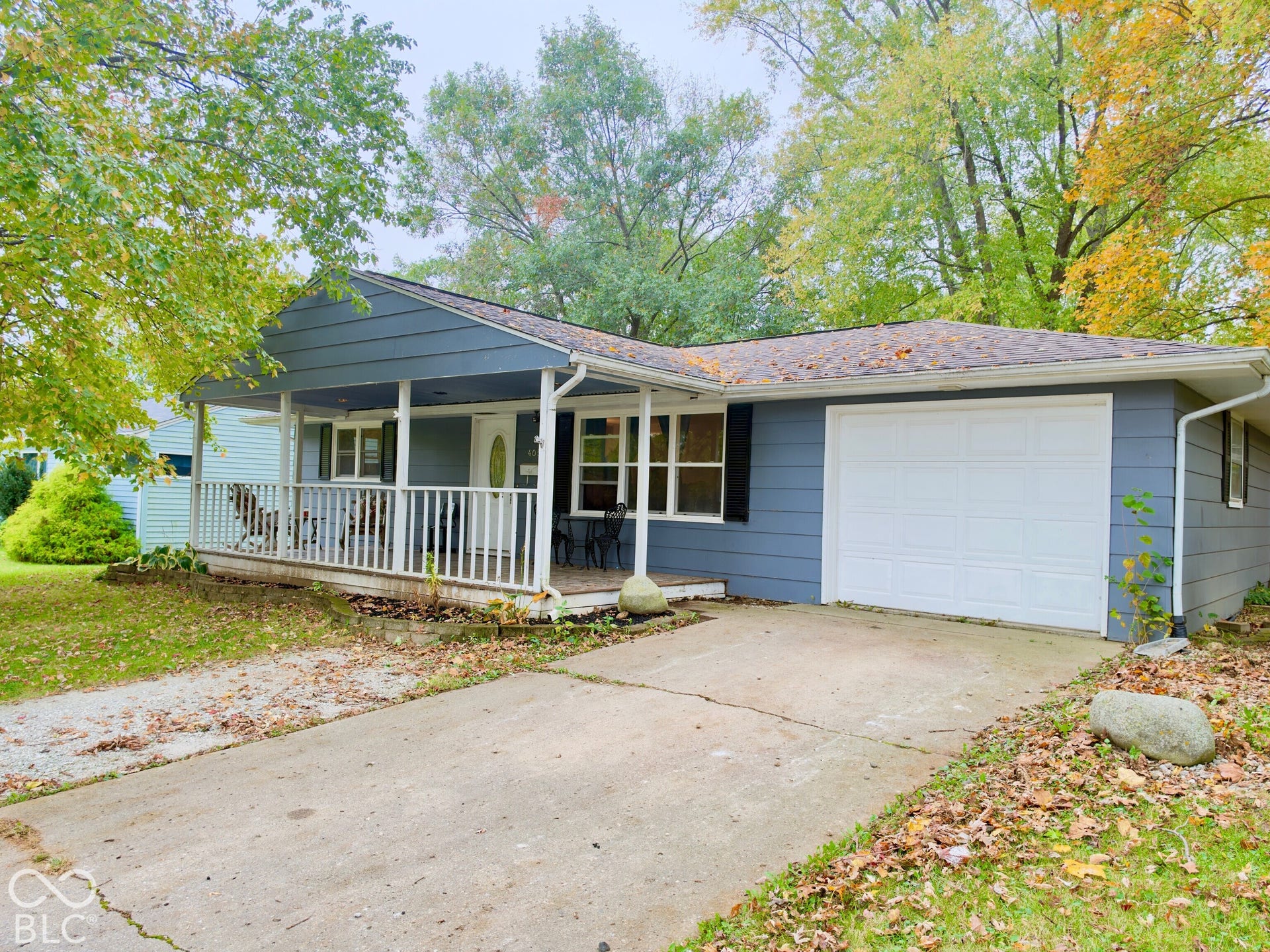 Single-story residence featuring horizontal lap siding, a covered front porch with white railing, and a single-car garage