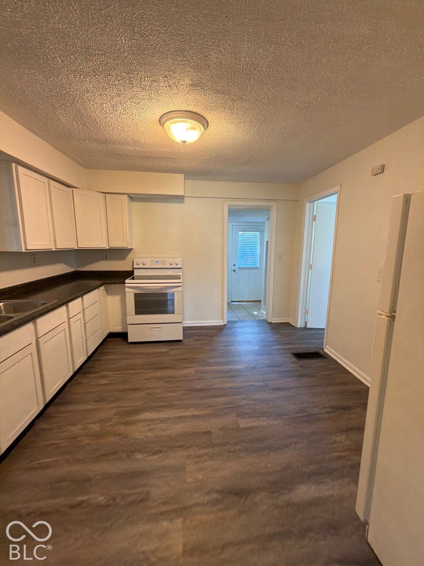 Kitchen featuring wood-finish flooring, white cabinetry, a white electric range, and a white refrigerator