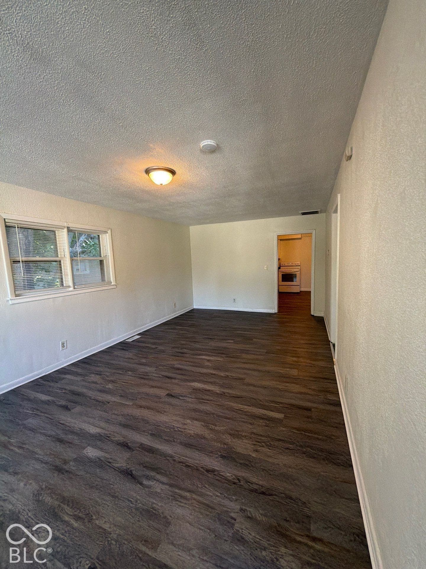 Wood-finish flooring throughout, paired with light-toned walls and a textured ceiling