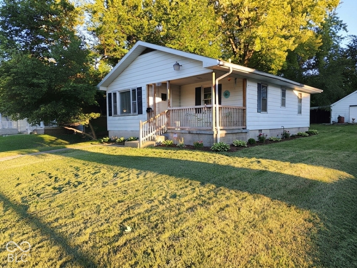 Virtually Altered - Charming cottage-style home featuring a covered front porch with wood railings, white exterior siding, and a peaked roof