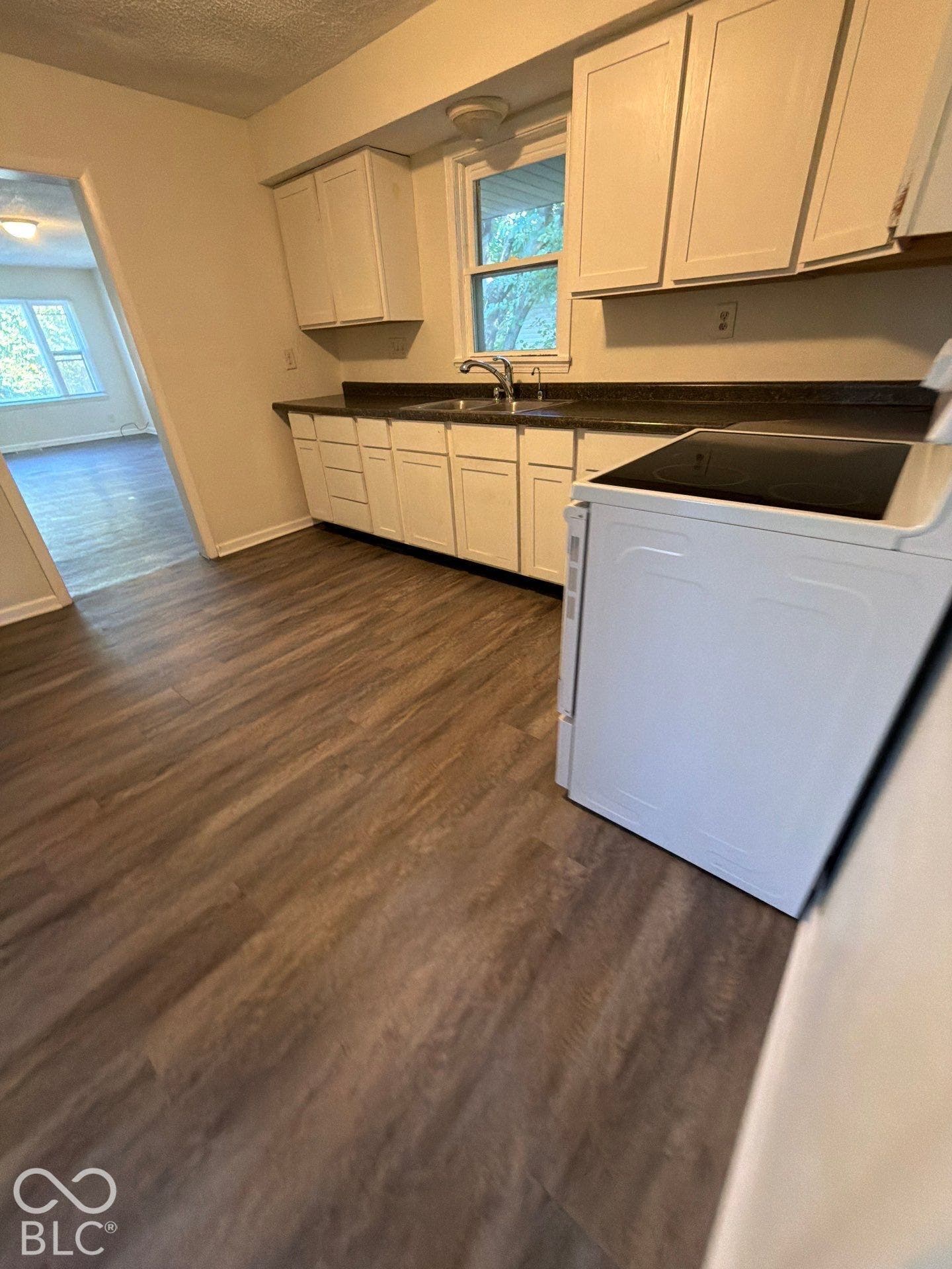 Kitchen featuring wood-finish flooring, white cabinetry, a stainless steel sink, and a range