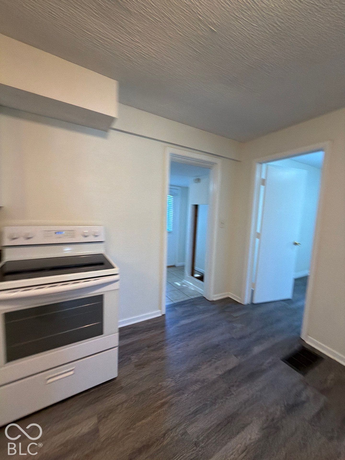 White electric range, wood-finish flooring, and white interior doors
