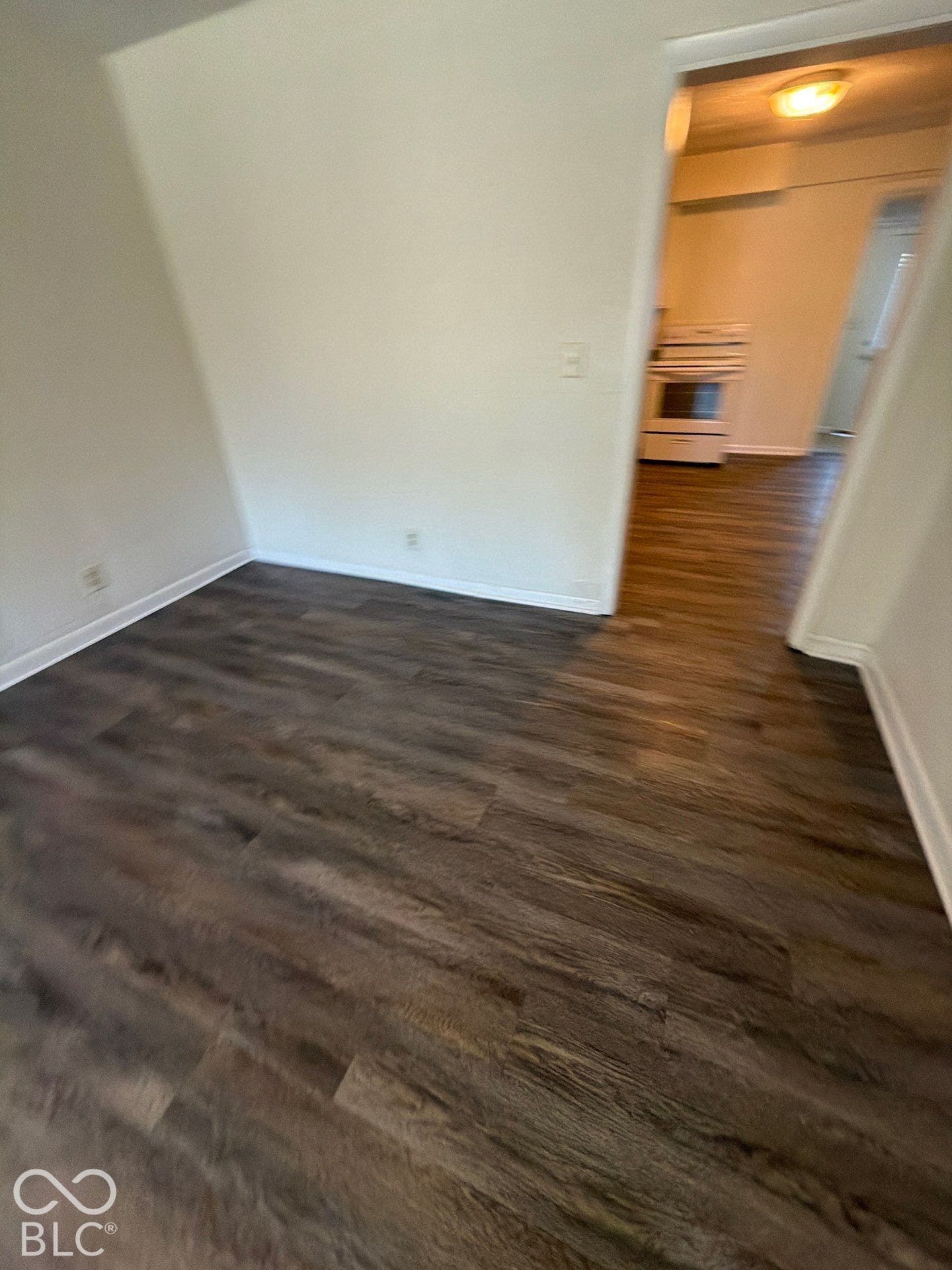 Spacious interior featuring dark wood-finish flooring and bright white walls with recessed lighting