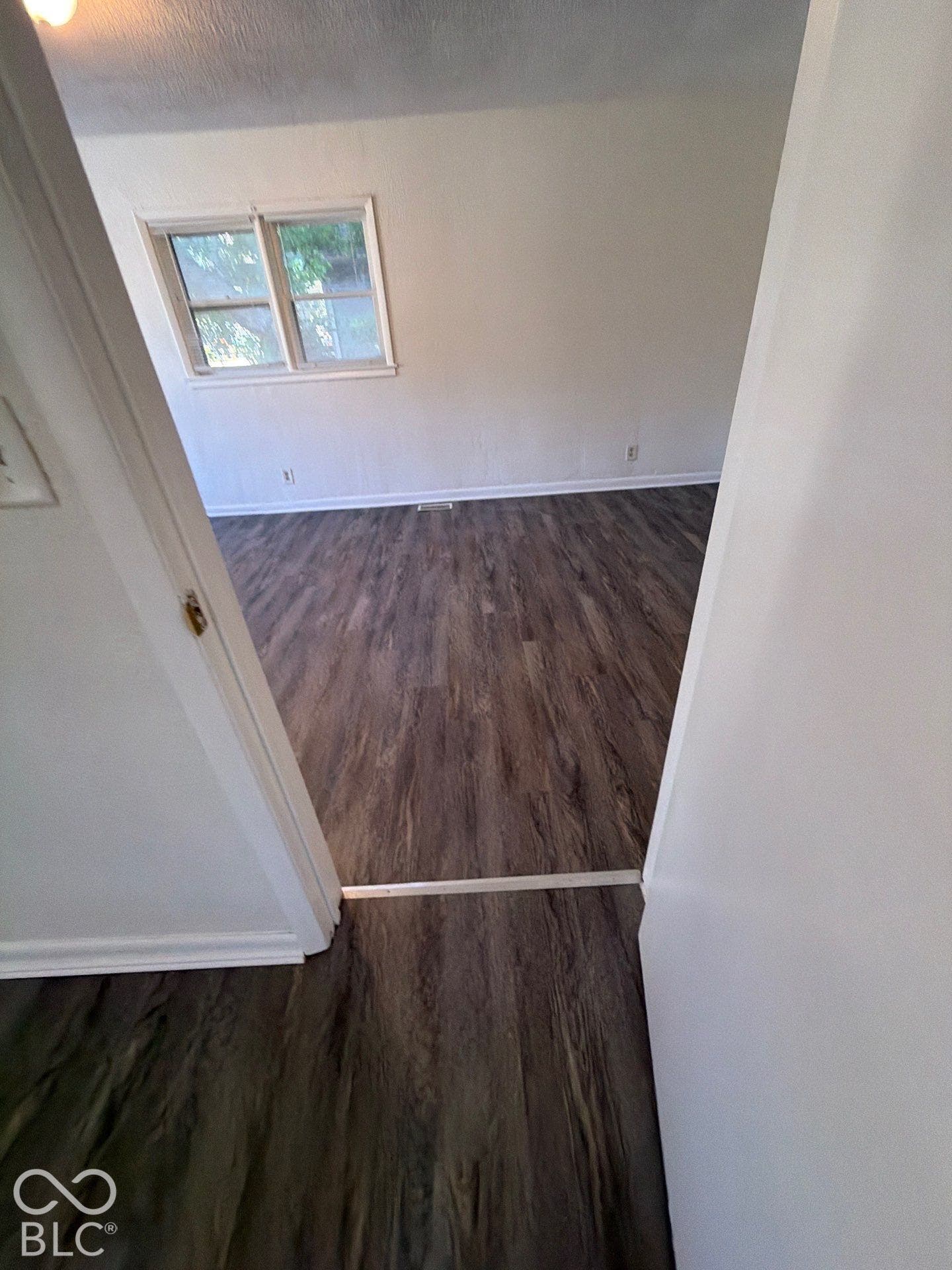 Wood-finish flooring throughout, white wall finishes, and a window with natural light