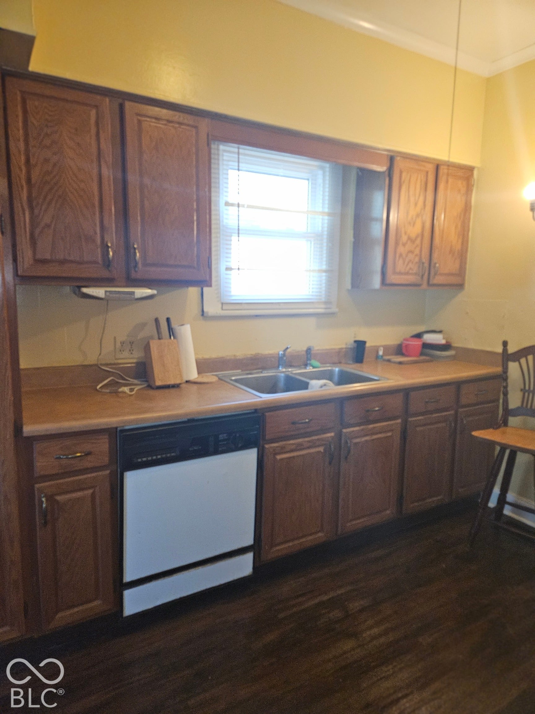 Wood-finish cabinetry with silver hardware, dual basin stainless steel sink, wood-finish countertops, and wood-finish flooring
