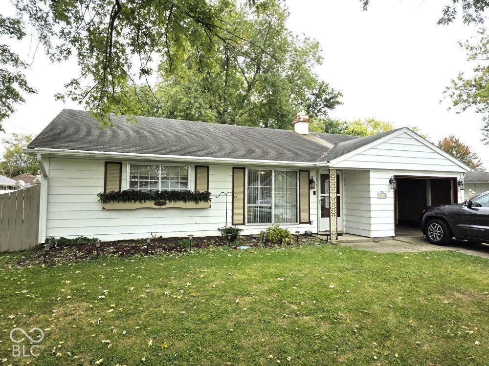 White siding exterior with a dark shingle roof, attached single-car garage, and a front lawn