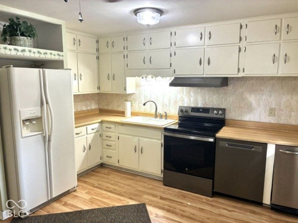 Featuring a side-by-side refrigerator, sink with a garbage disposal, and lots of cabinetry for storage!