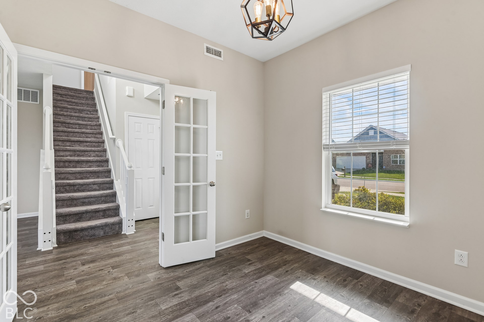 Room featuring French doors, viny wood-finish flooring, a geometric pendant light fixture, and a single-hung window with blinds