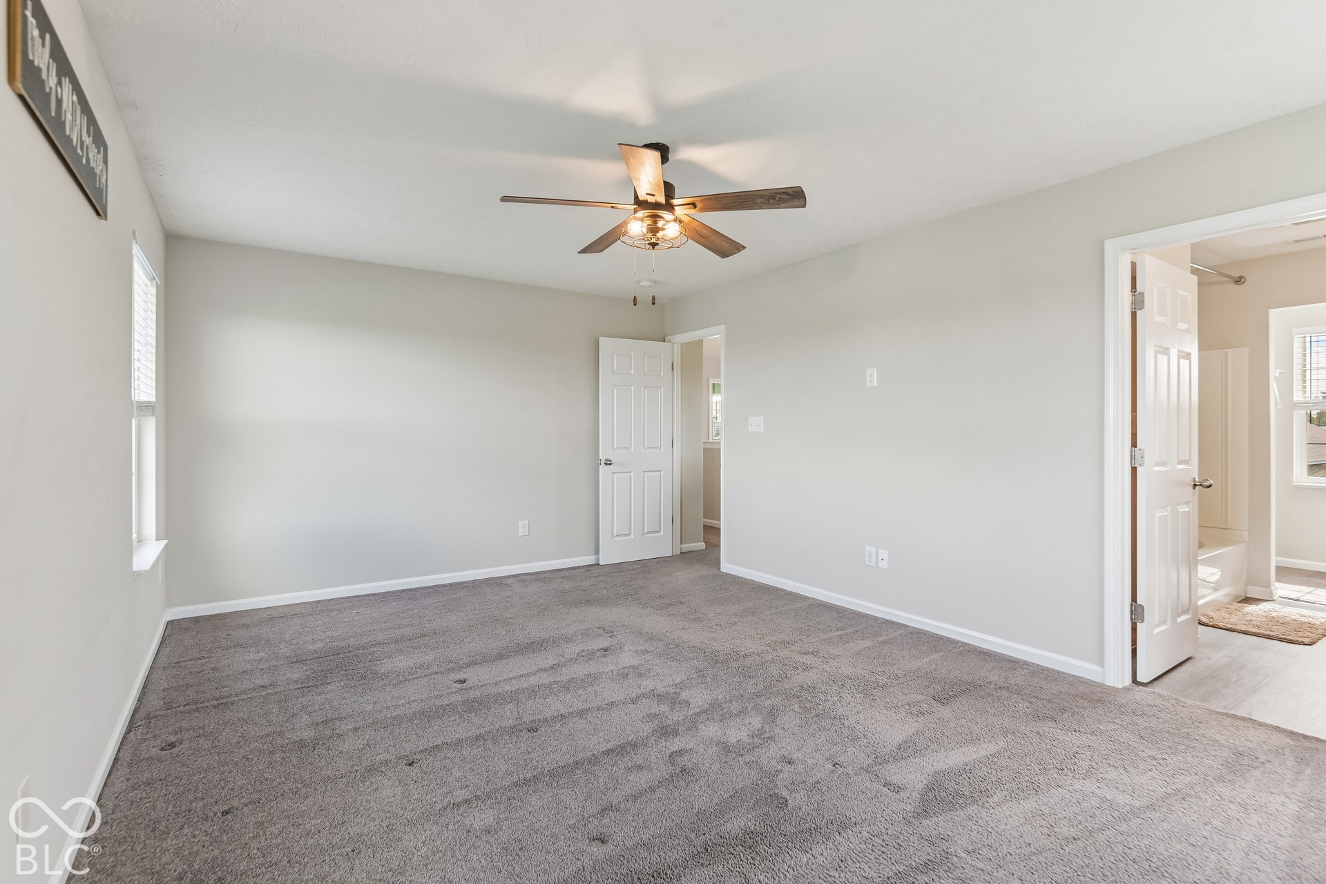 Neutral wall tones, wall-to-wall carpeting, ceiling fan with integrated lighting, and six-panel interior doors