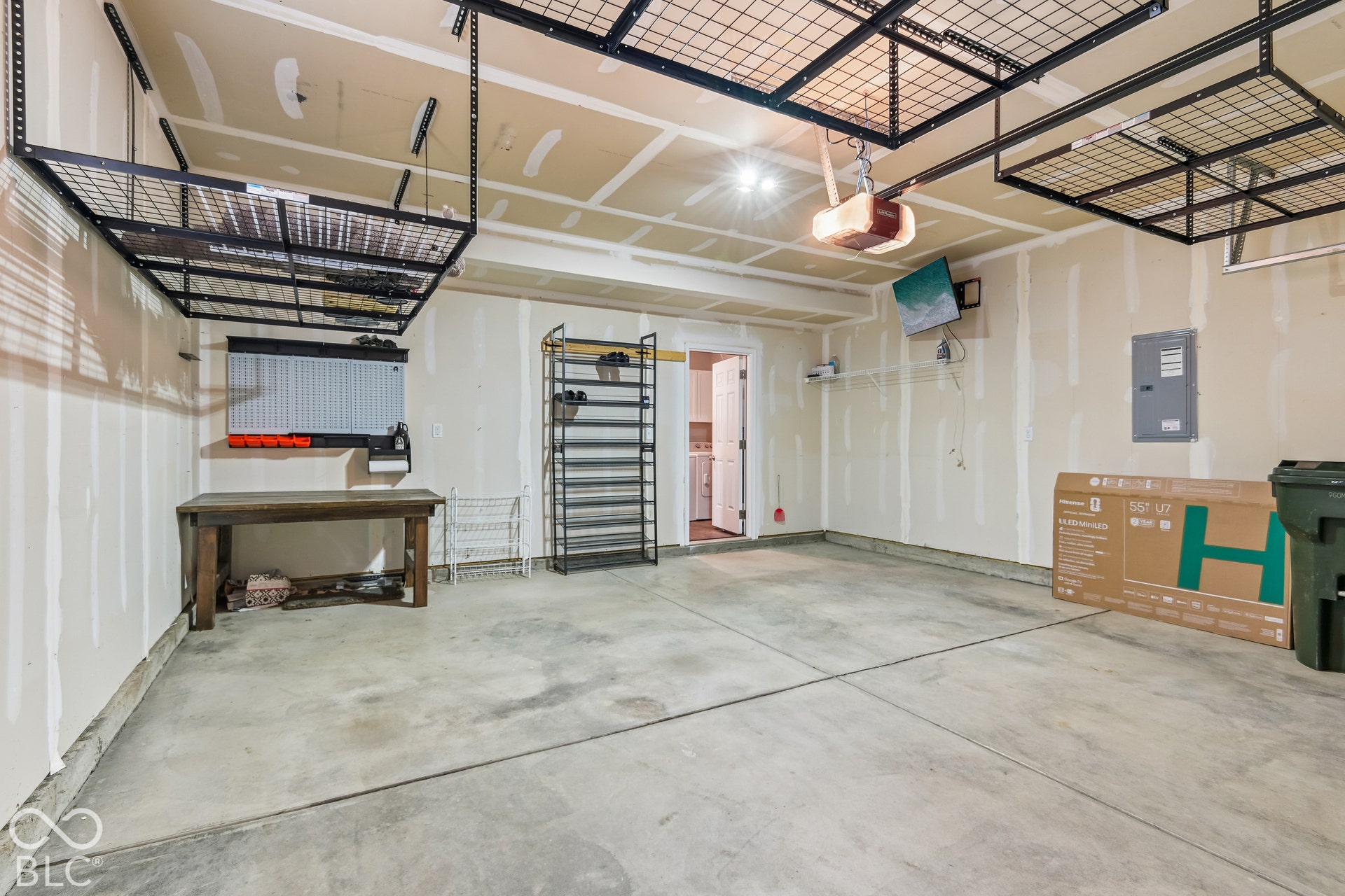 Multi-car garage featuring overhead storage racks, concrete flooring, and an electrical subpanel