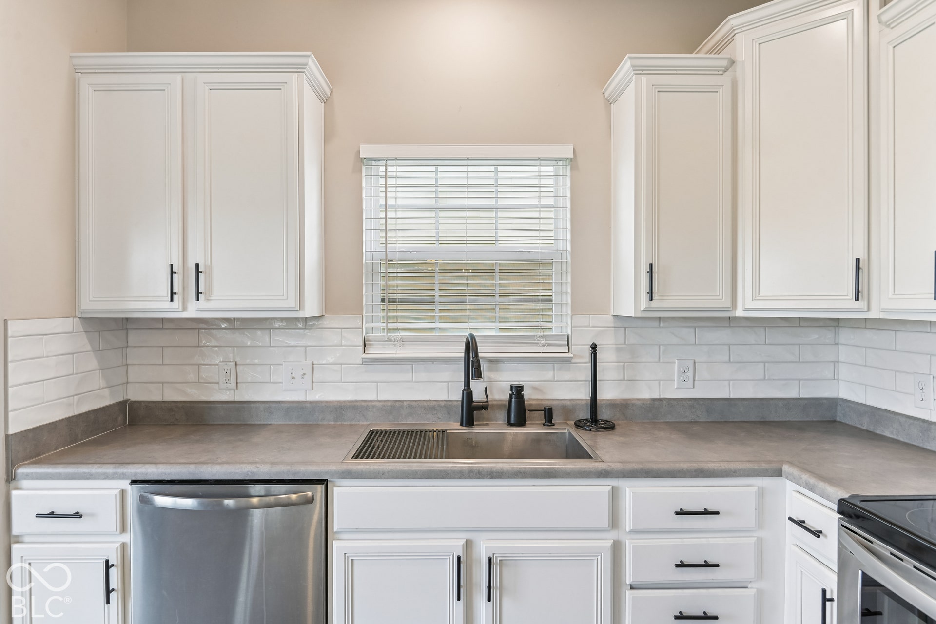 Kitchen featuring white shaker-style cabinetry, matte black hardware, subway tile backsplash, stainless steel sink with a high-arch faucet