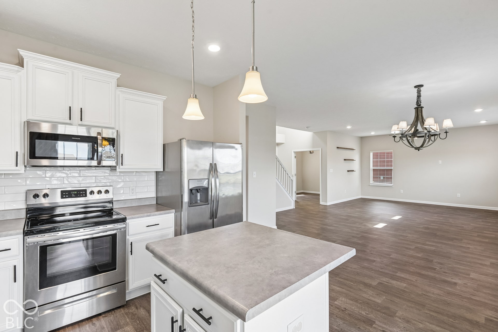 Kitchen featuring white shaker-style cabinetry, stainless steel appliances, subway tile backsplash, and vinyl wood-finish flooring