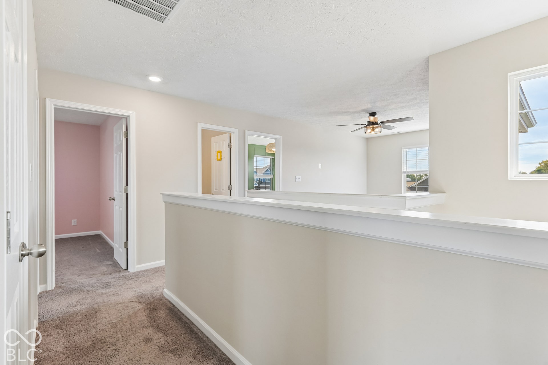 Hallway featuring wall-to-wall carpeting, white painted trim, multiple interior doorways, recessed lighting, and a ceiling fan with integrated light fixture