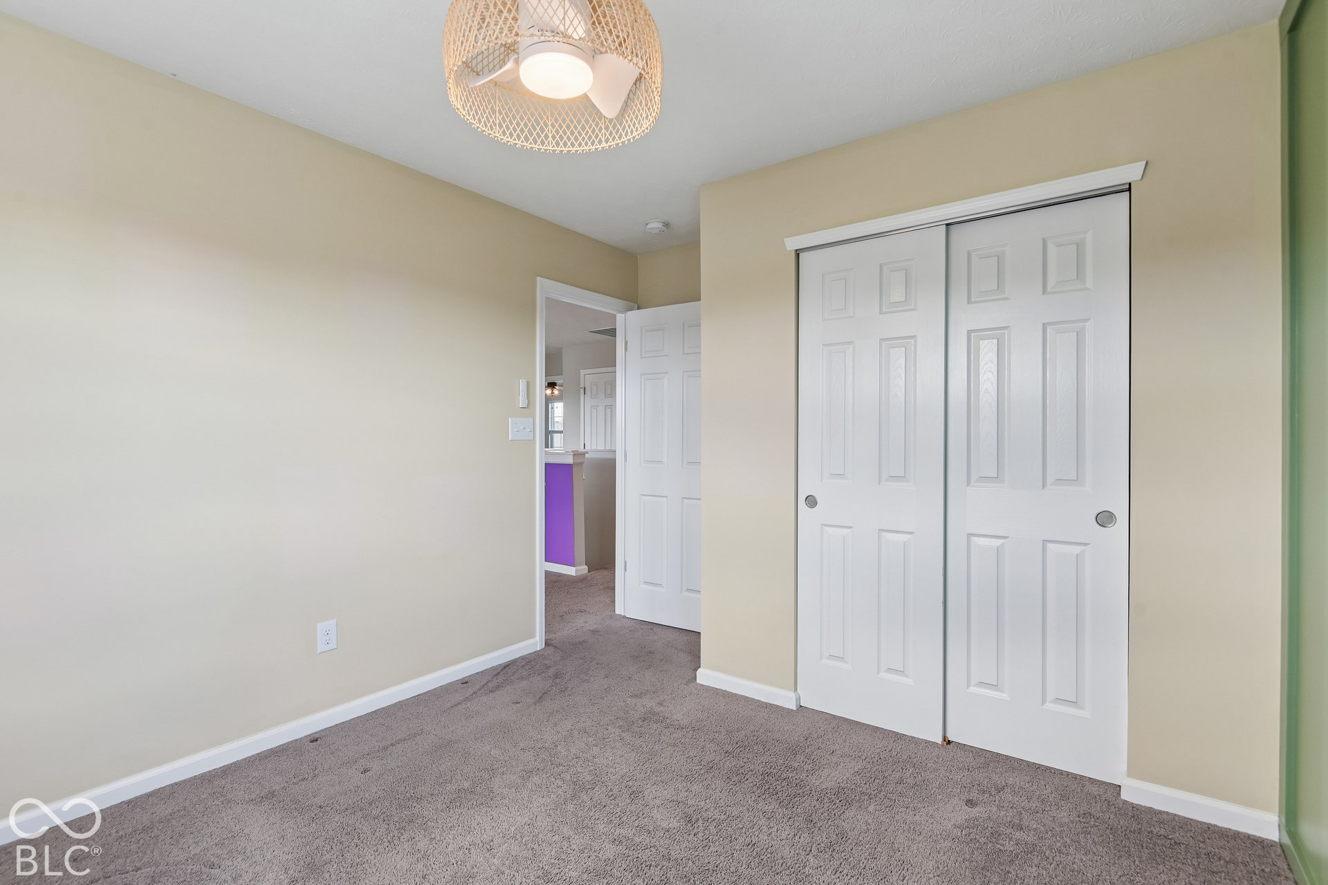 Room featuring neutral-toned walls, carpeting, a woven pendant light fixture, and a white six-panel sliding door closet
