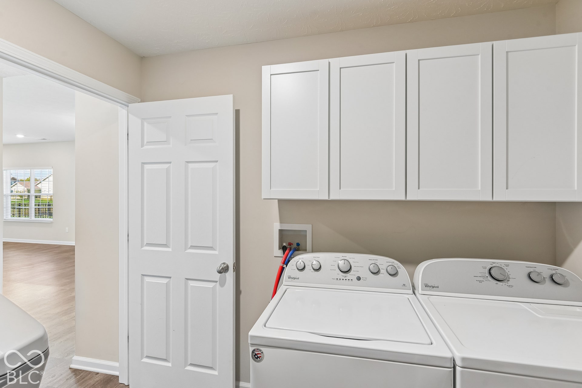 Laundry area featuring white shaker-style wall-mounted cabinetry, a recessed utility connection box, and a six-panel interior door, washer, and dryer included