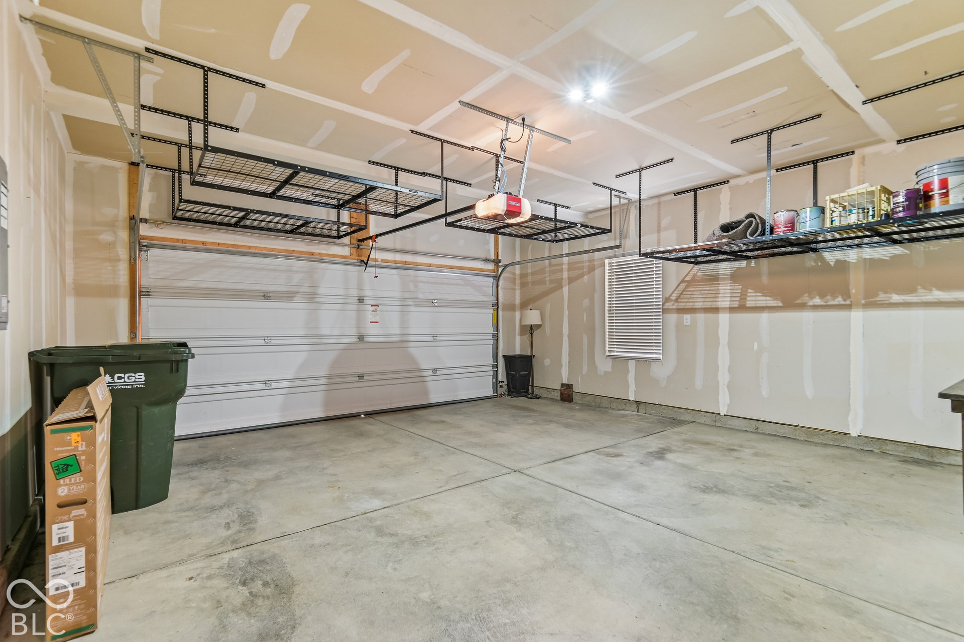 Multi-car garage featuring a concrete floor, sectional overhead door, and integrated metal ceiling-mounted storage racks