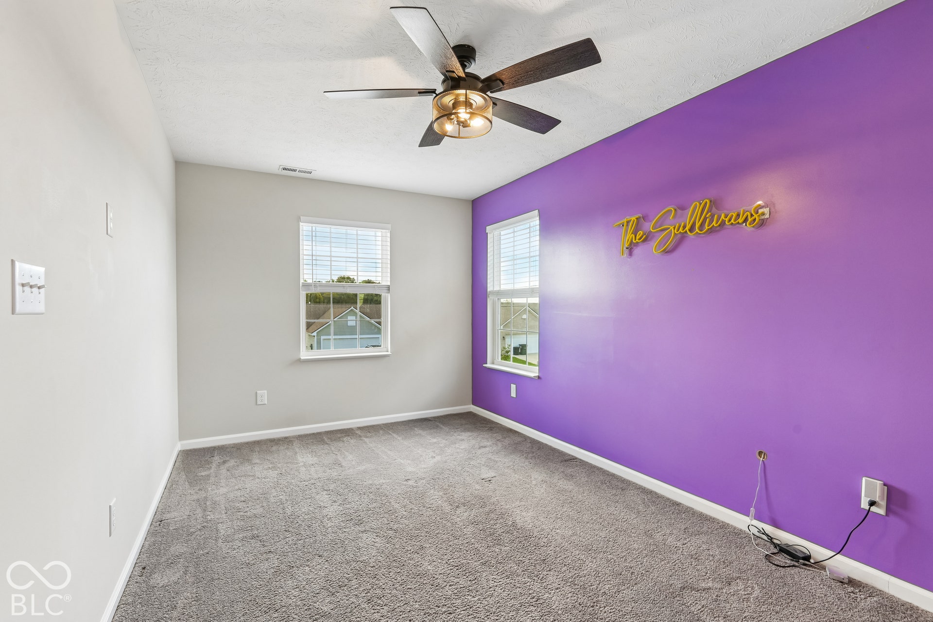 Neutral-toned room featuring plush carpeting, dual double-pane windows, and a multi-blade ceiling fan with an integrated light fixture