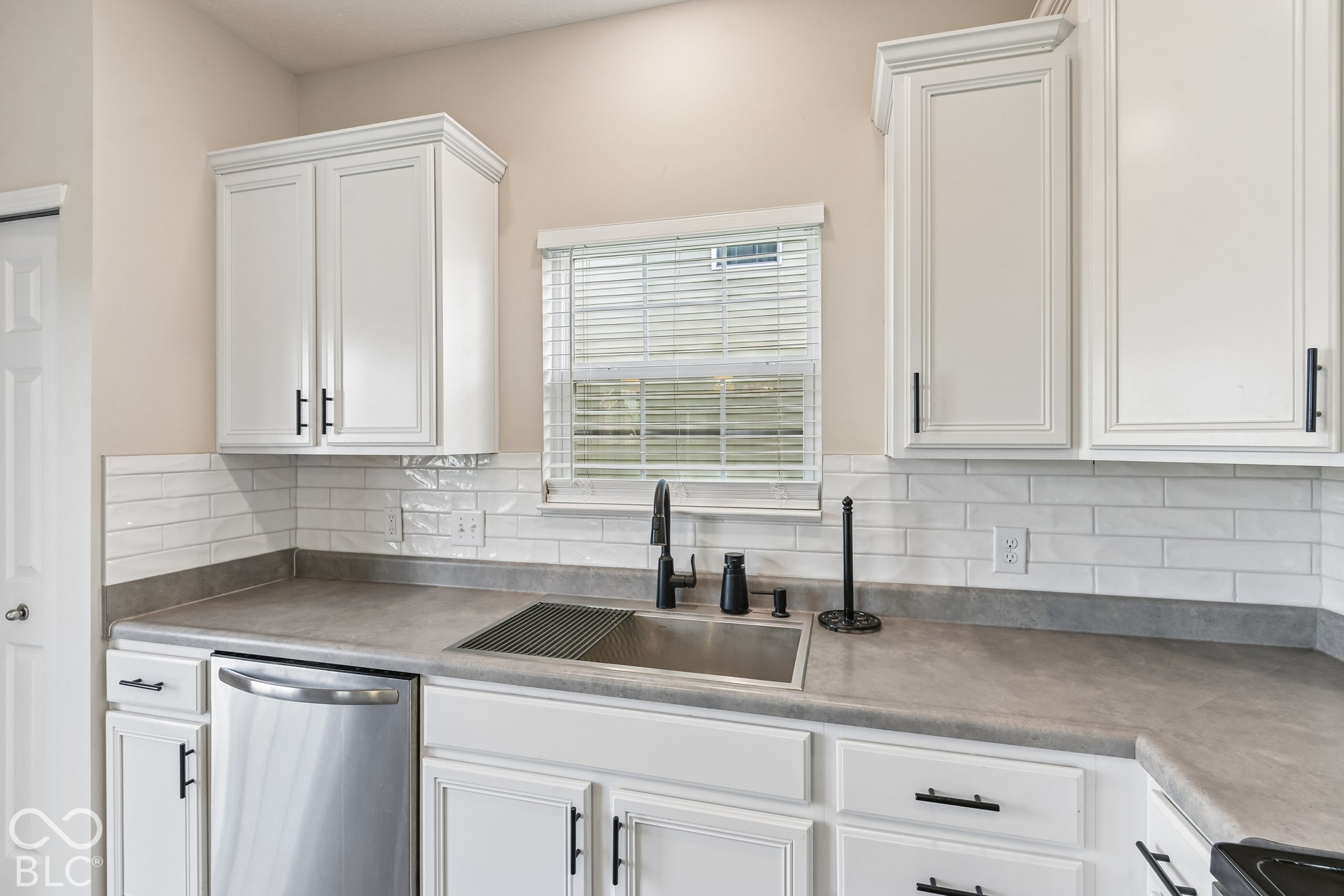 Kitchen featuring white shaker-style cabinetry, matte black hardware,subway tile backsplash, and a stainless steel undermount sink with a matte black pull-down faucet