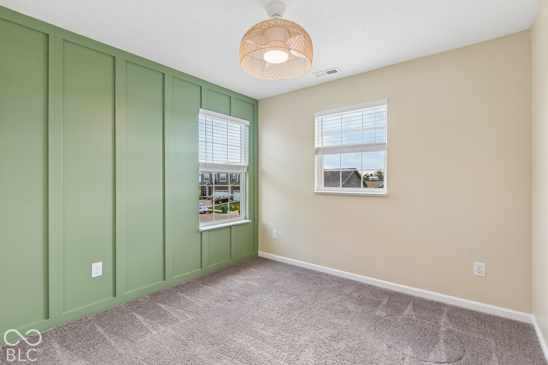 Accent wall featuring board and batten millwork, neutral carpeting, two windows with integrated blinds, and a dome-style semi-flush mount light fixture
