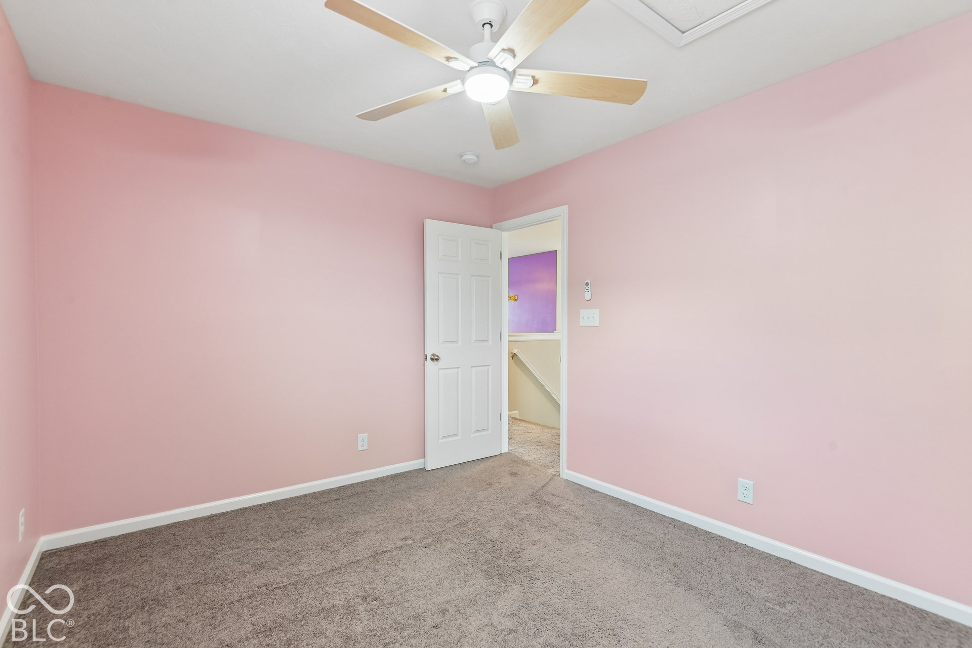 Room featuring wall-to-wall carpeting, a six-panel interior door, and a central ceiling fan with integrated lighting