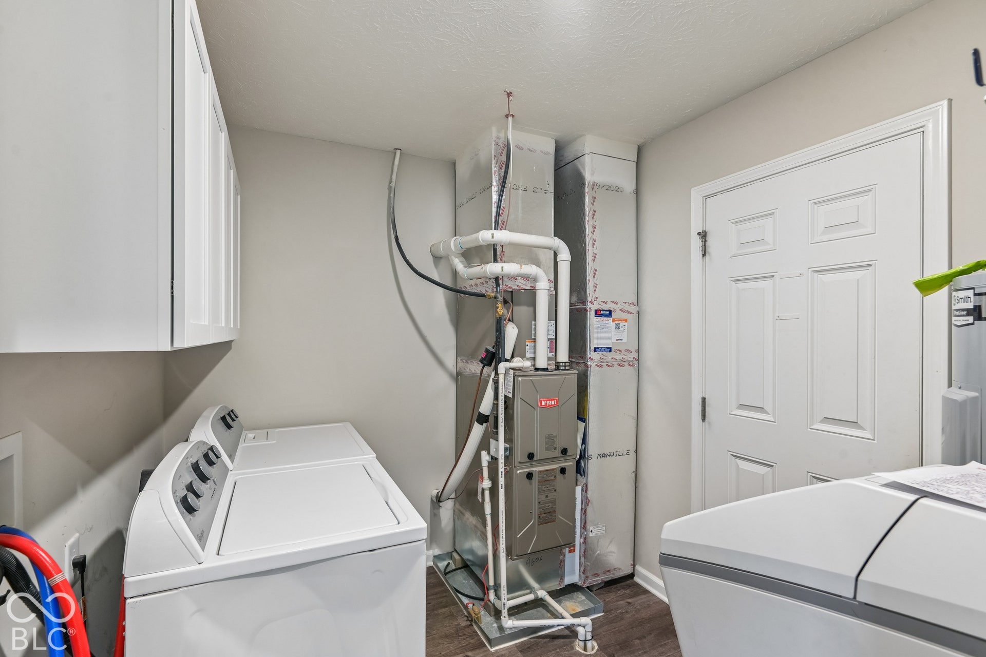 Utility room featuring white wall-mounted cabinetry, a high-efficiency HVAC system, and vinyl  wood-finish flooring