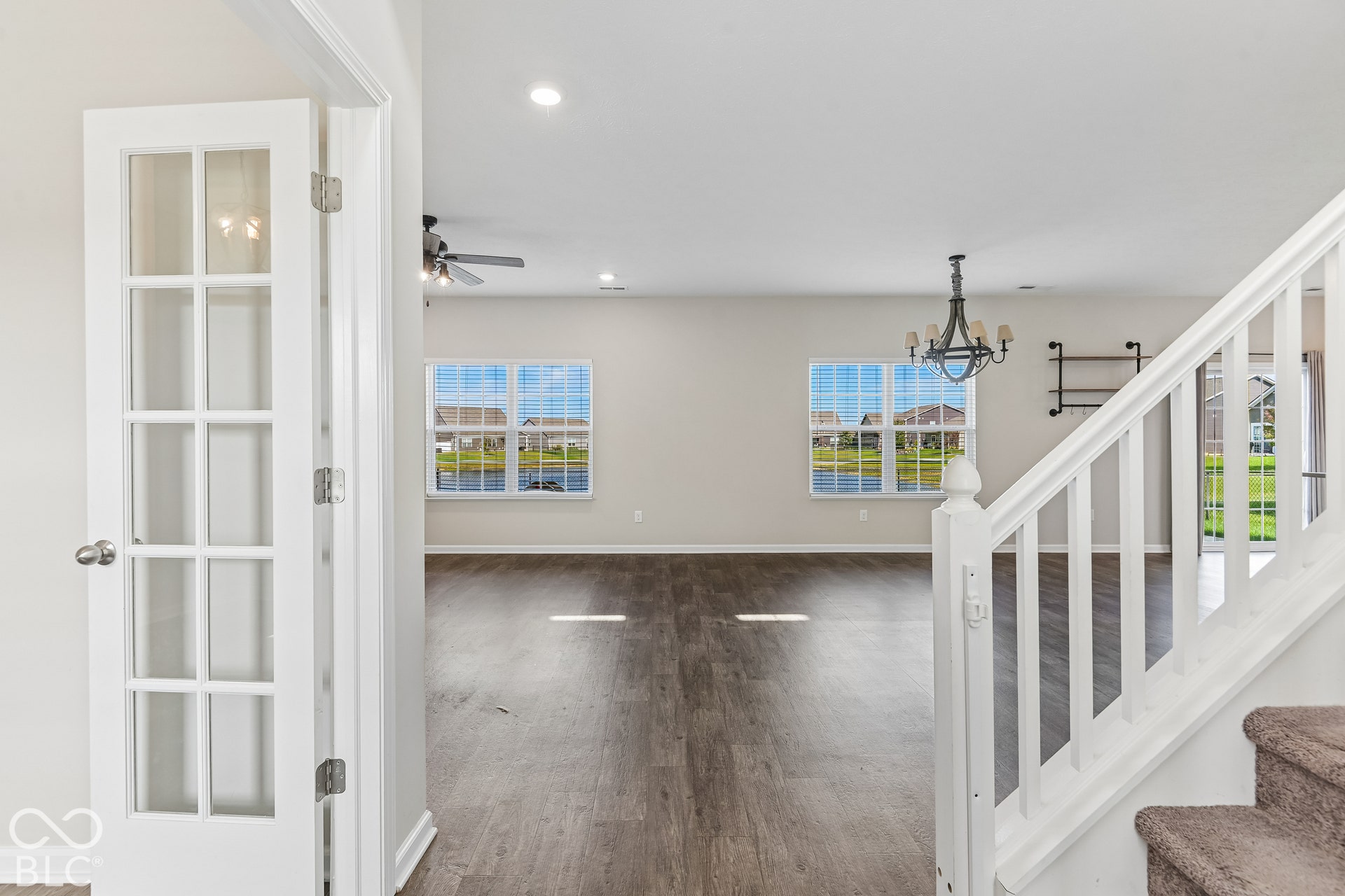 Interior space featuring vinyl wood-finish flooring, white French doors, a staircase with a white balustrade, recessed lighting, and a multi-arm chandelier