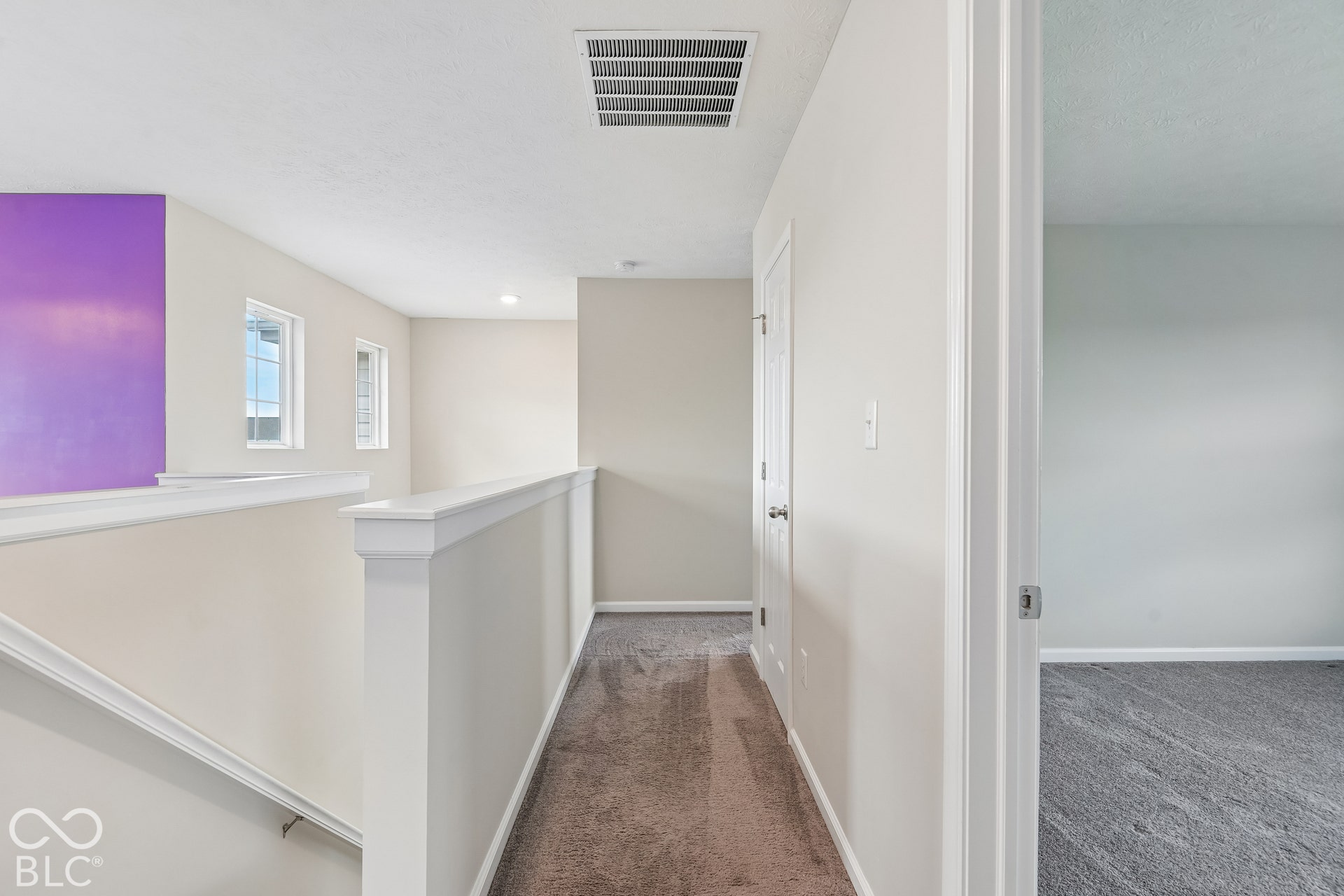 Interior hall featuring neutral wall paint, carpeted flooring, and a painted wooden railing