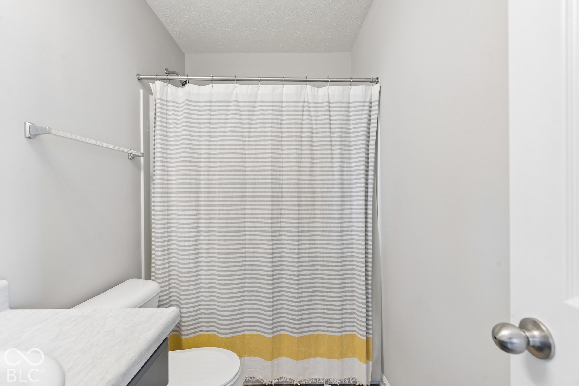 Bathroom featuring a stone-composite countertop, white toilet, and a bathtub with a metal curtain rod