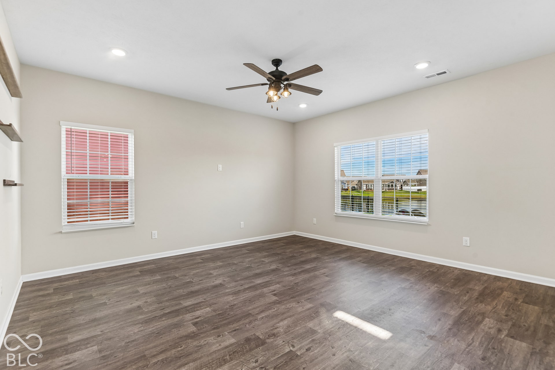Neutral interior space featuring  vinyl wood-finish flooring, recessed lighting, a central ceiling fan with integrated light fixture, and windows with horizontal blinds