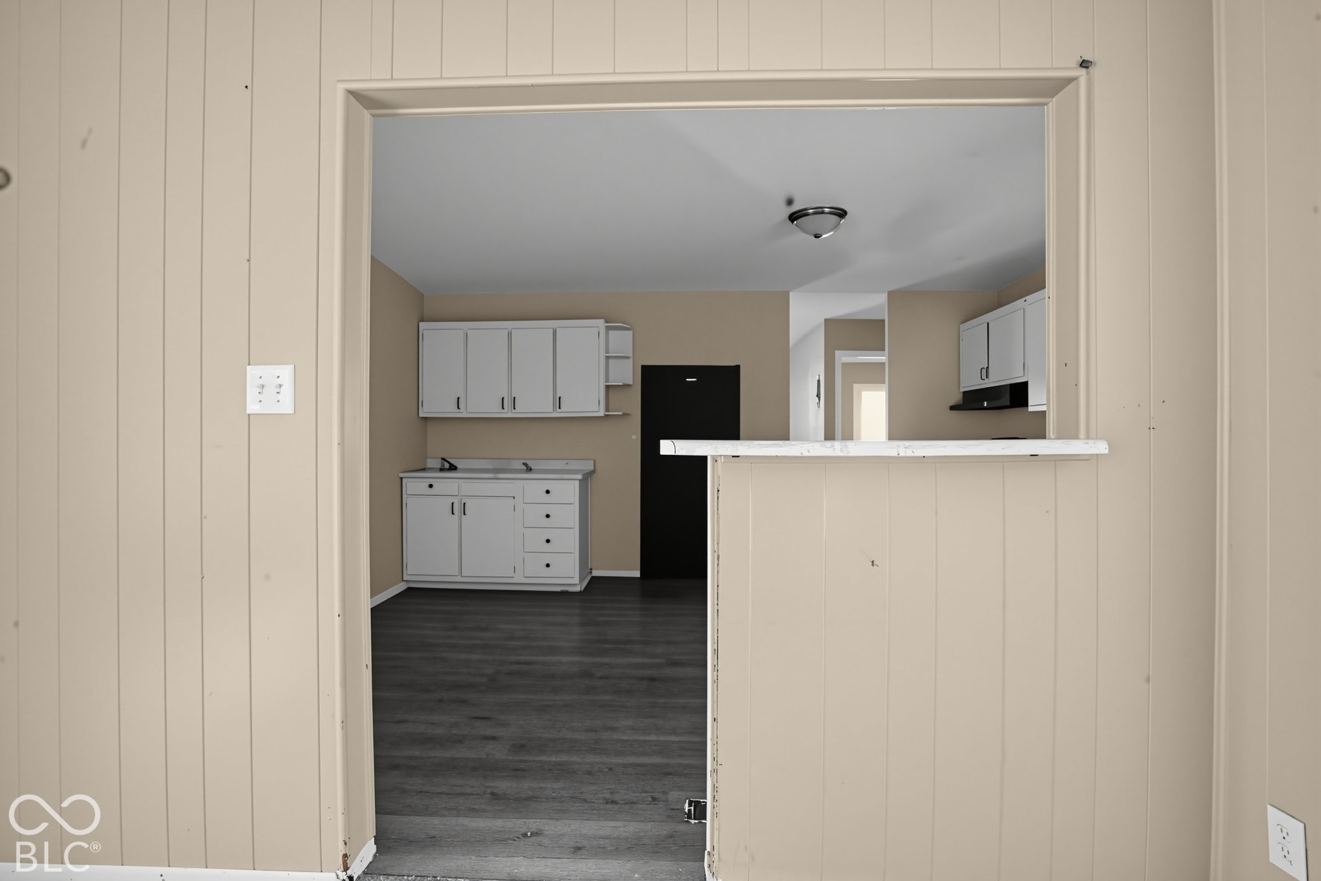 Kitchen featuring white cabinetry, a pass-through opening, a built-in counter surface, and wood-finish flooring