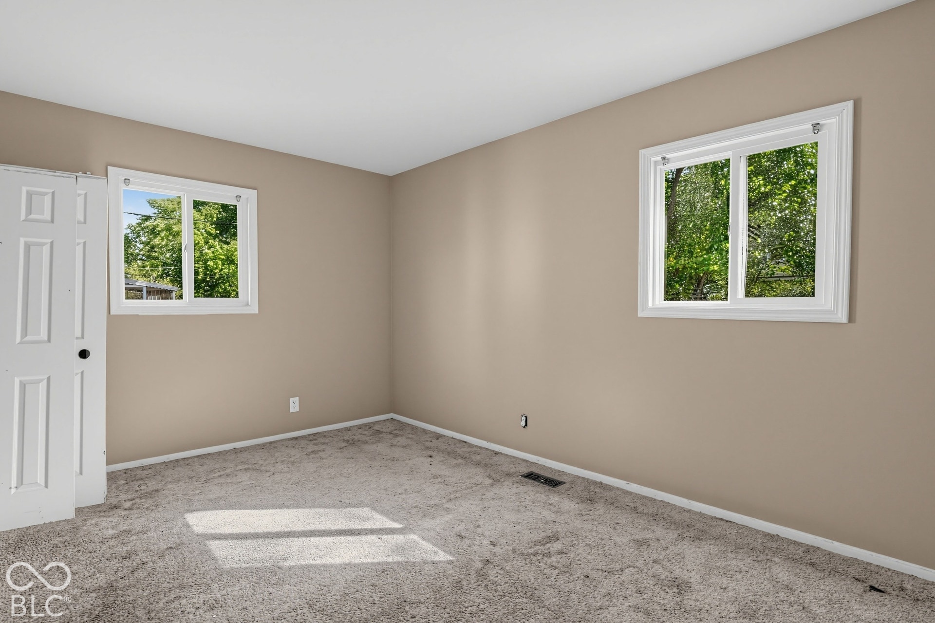 Room featuring neutral wall tones, two dual-pane sliding windows, and a built-in folding closet door