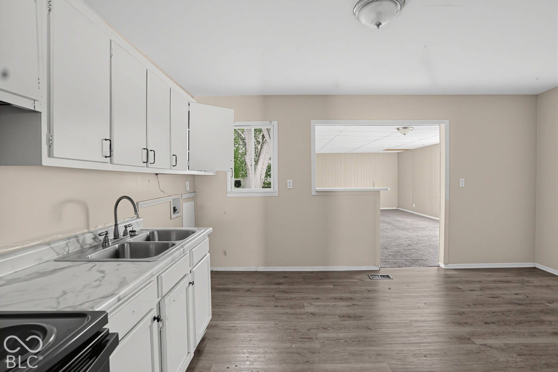 Kitchen featuring white cabinetry, stone-finish countertops, stainless steel dual-basin sink with high-arc faucet, and wood-finish flooring