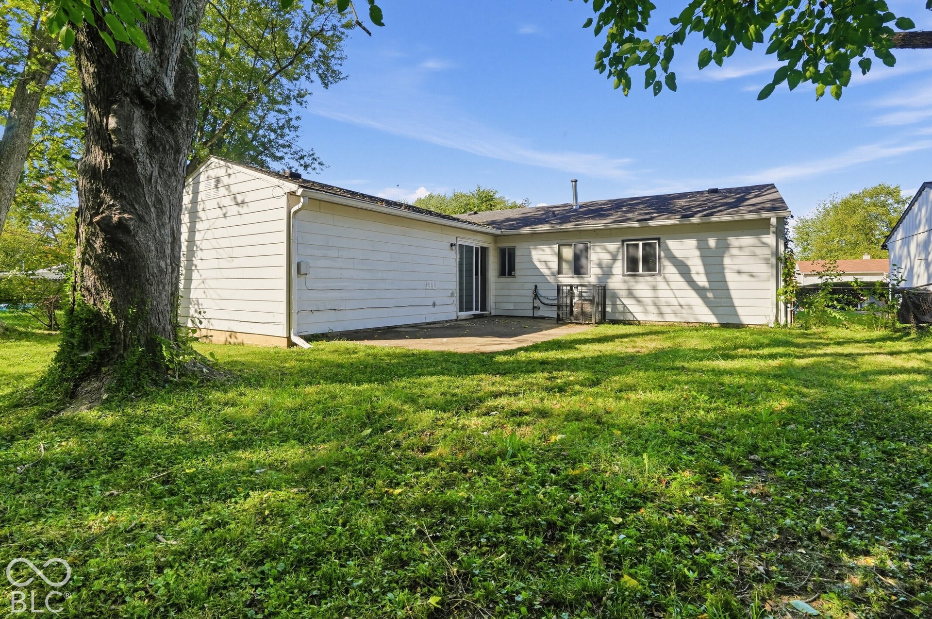 Exterior featuring horizontal siding, concrete patio, sliding glass door, and mature trees