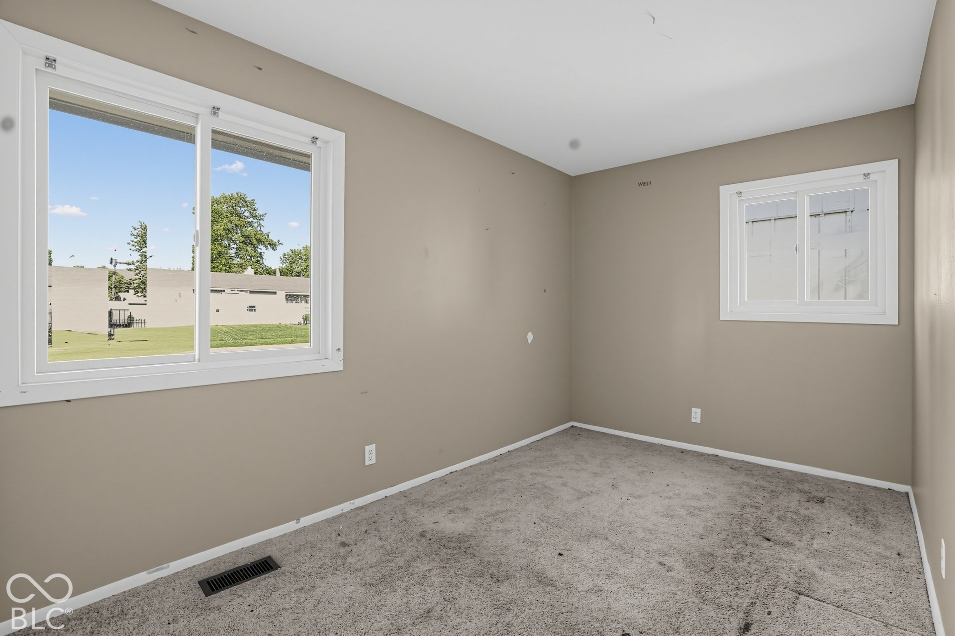 Neutral-toned room featuring wall-to-wall carpeting and dual sliding windows