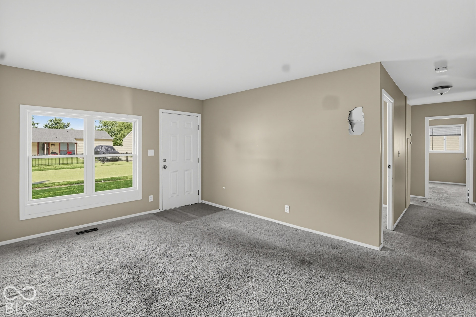 Spacious living area featuring neutral wall finishes, plush carpeting, and abundant natural light from French doors opening to the exterior