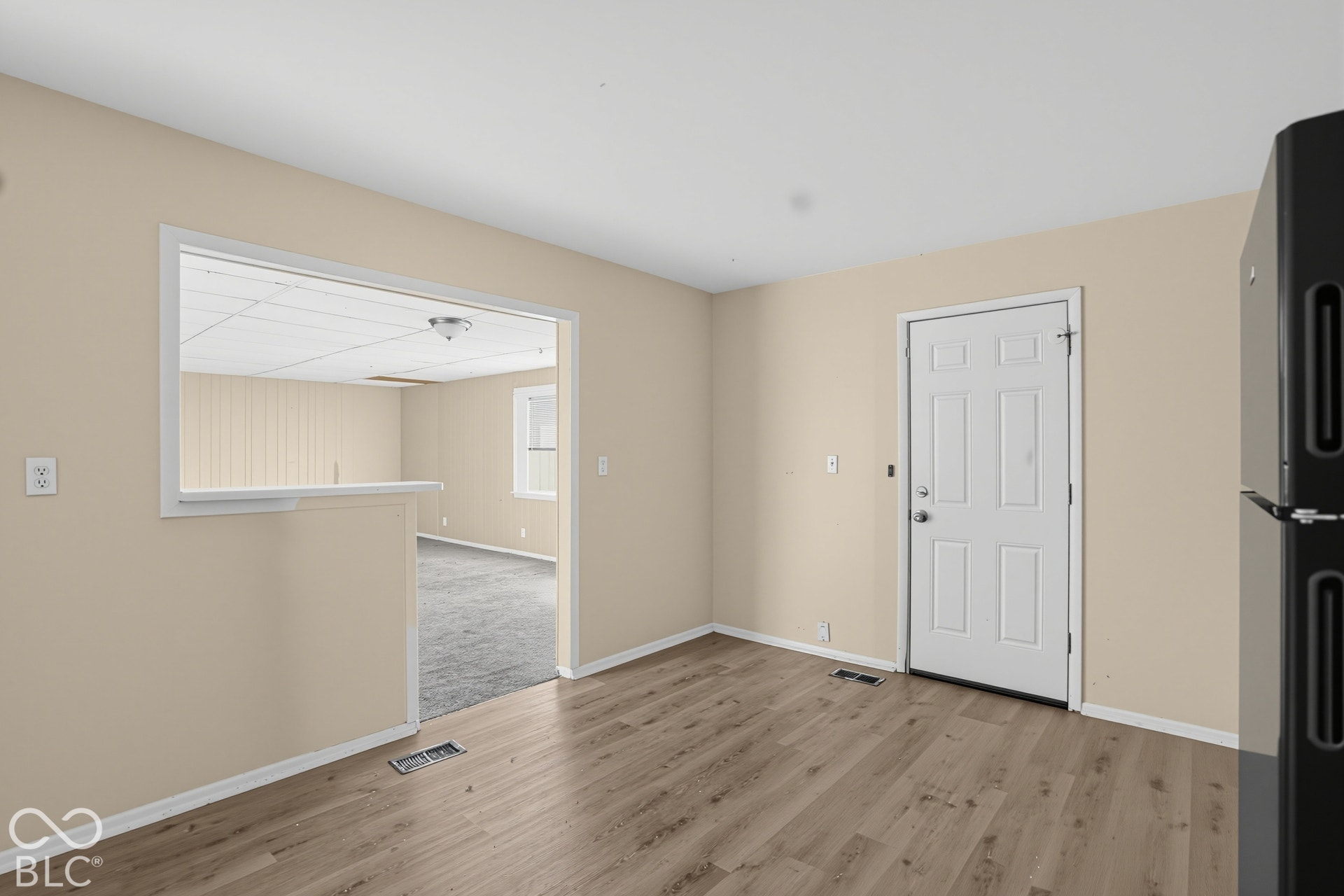 Wood-finish flooring, interior six-panel door, and open wall pass-through