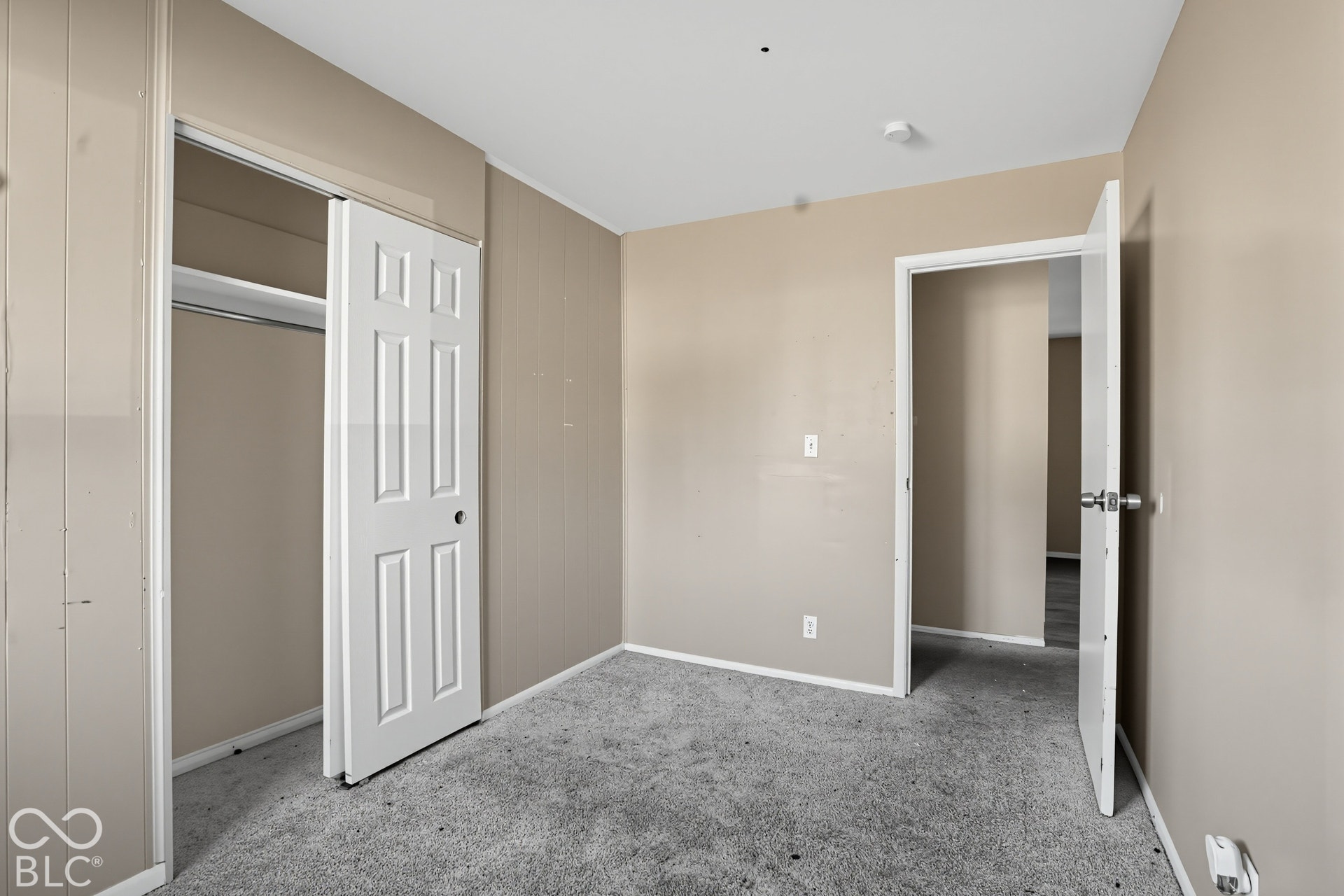 Neutral-toned interior space featuring carpeting, a multi-panel door leading to a closet, and a multi-panel passage door