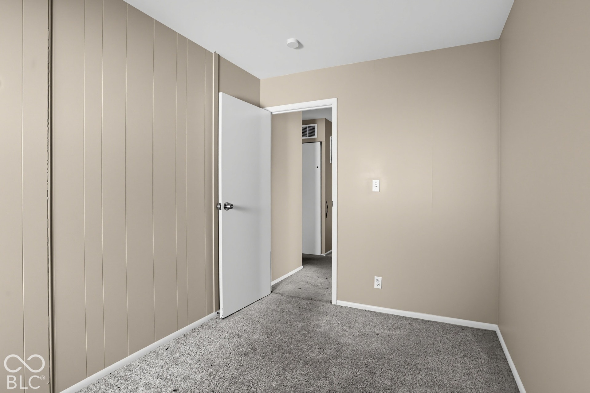 Interior space featuring vertical panel walls, neutral paint finish, and wall-to-wall carpeting