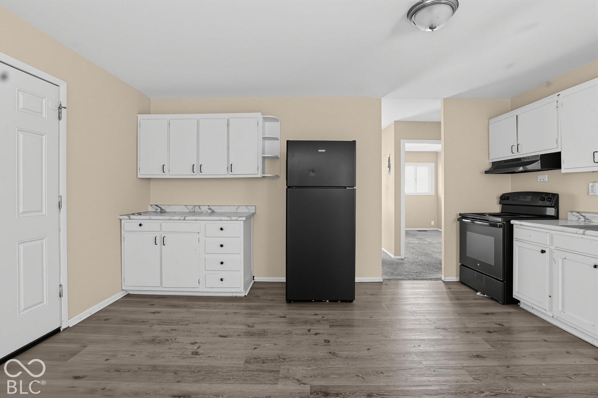 Kitchen featuring wood-finish flooring, white cabinetry, stone-patterned countertops, and a black refrigerator and stove